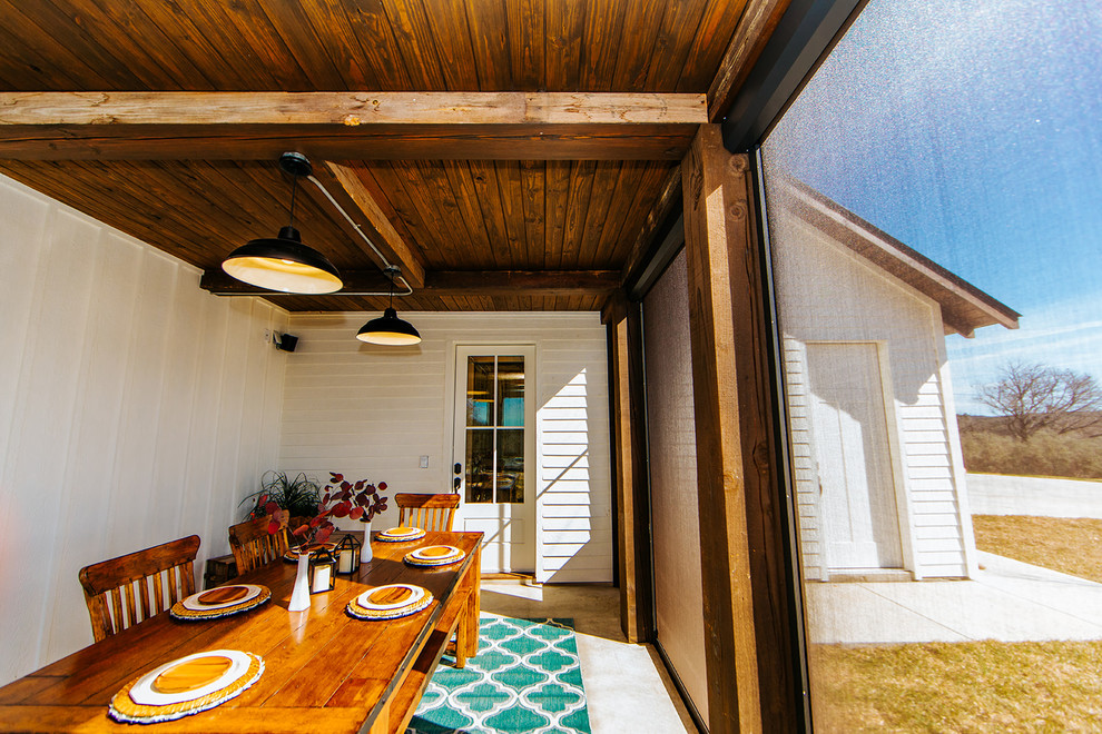 Inspiration pour un grand porche d'entrée de maison latéral rustique avec une moustiquaire, une dalle de béton et une extension de toiture.
