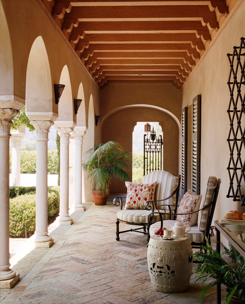 Réalisation d'un porche d'entrée de maison méditerranéen avec des pavés en pierre naturelle et une extension de toiture.
