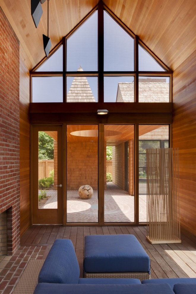 Exemple d'un très grand porche d'entrée de maison arrière moderne avec une moustiquaire, des pavés en brique et une extension de toiture.