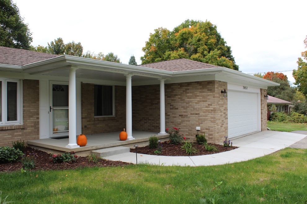 This is an example of a mid-sized 1960s concrete front porch design in Other with a roof extension.