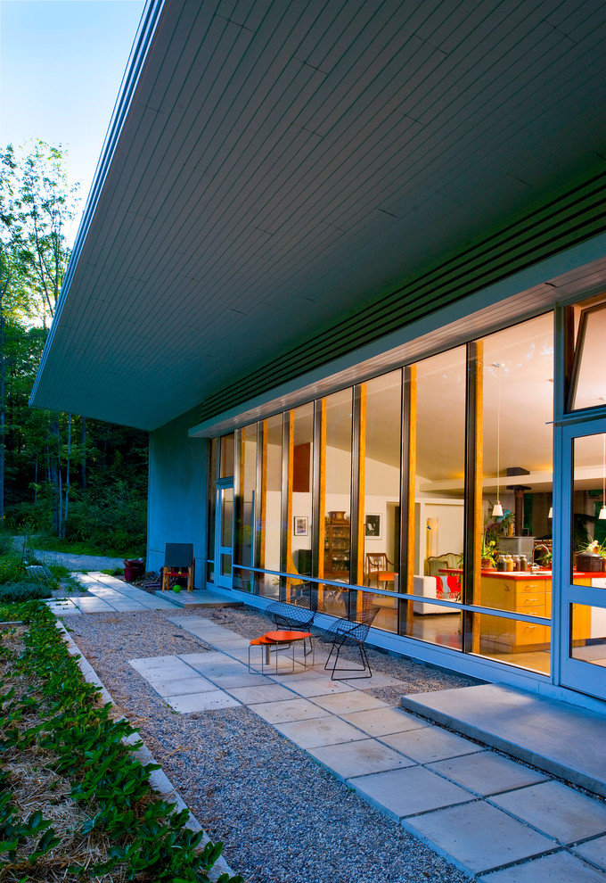 Idée de décoration pour un porche d'entrée de maison design avec des pavés en béton et une extension de toiture.