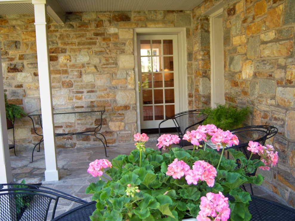 Inspiration för mellanstora amerikanska verandor på baksidan av huset, med naturstensplattor och takförlängning