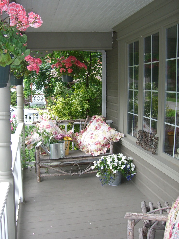 Shabby chic-inspirerad inredning av en mellanstor veranda framför huset, med trädäck och takförlängning