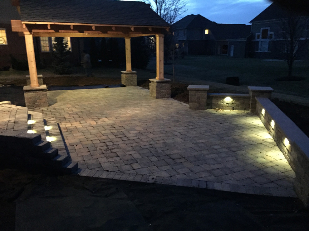 This is an example of a large contemporary brick porch design in Indianapolis with a pergola.