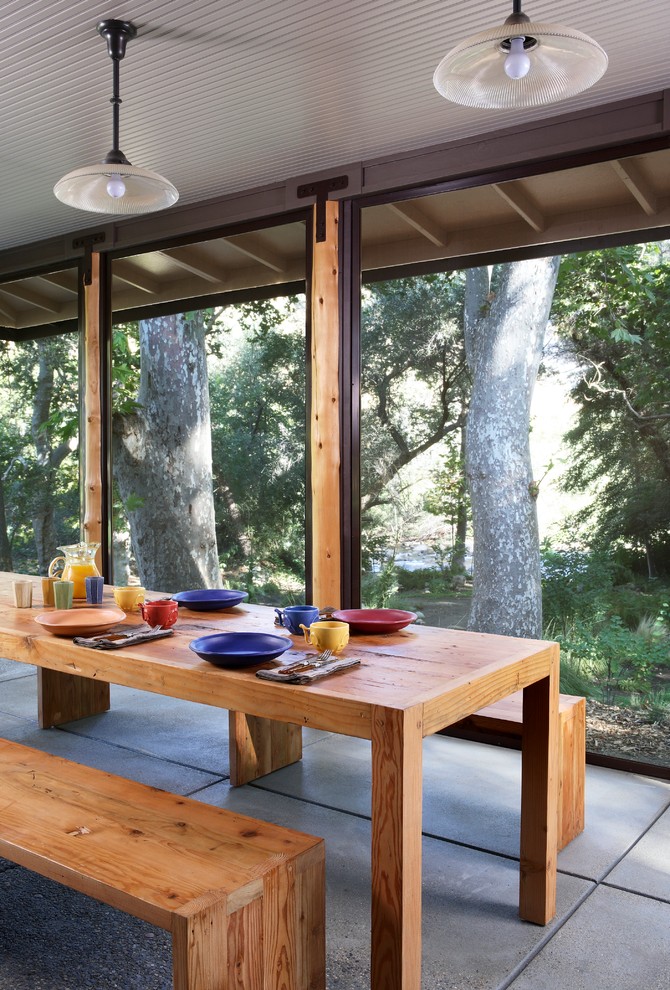Cette image montre un porche d'entrée de maison design avec une dalle de béton, une extension de toiture et une moustiquaire.
