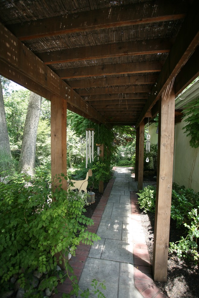 Idées déco pour un porche d'entrée de maison latéral classique avec des pavés en béton et une pergola.