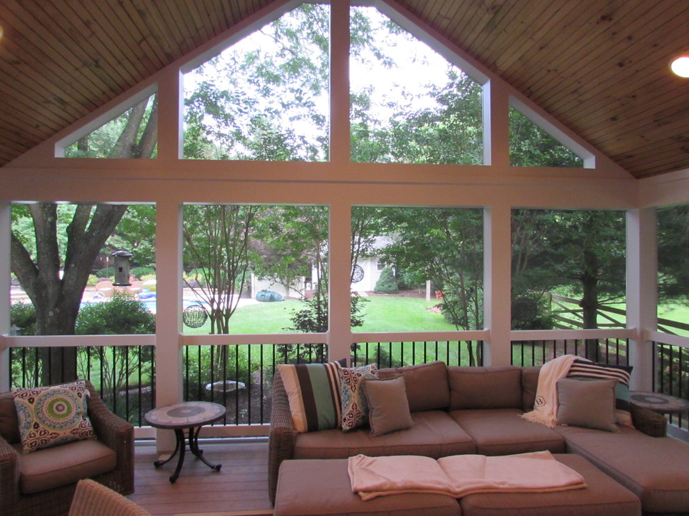 This is an example of a mid-sized transitional screened-in back porch design in DC Metro with a roof extension.