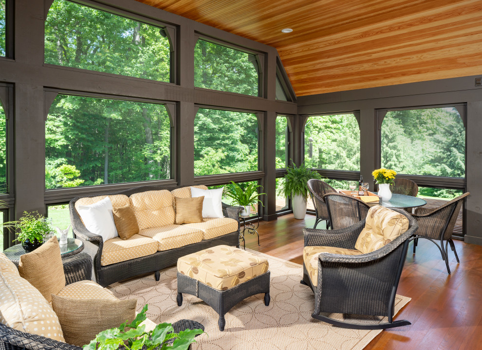Réalisation d'un grand porche d'entrée de maison arrière tradition avec une terrasse en bois et une extension de toiture.