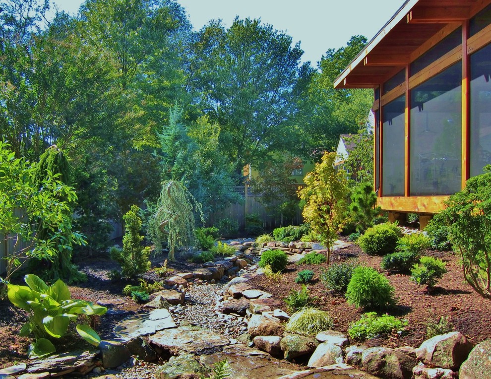 Réalisation d'un petit jardin arrière asiatique avec des pavés en pierre naturelle.