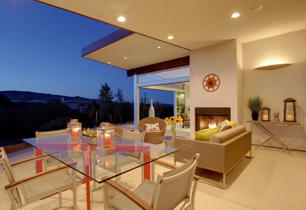 This is an example of a mid-sized 1950s concrete side porch design in Los Angeles with a fire pit and a roof extension.