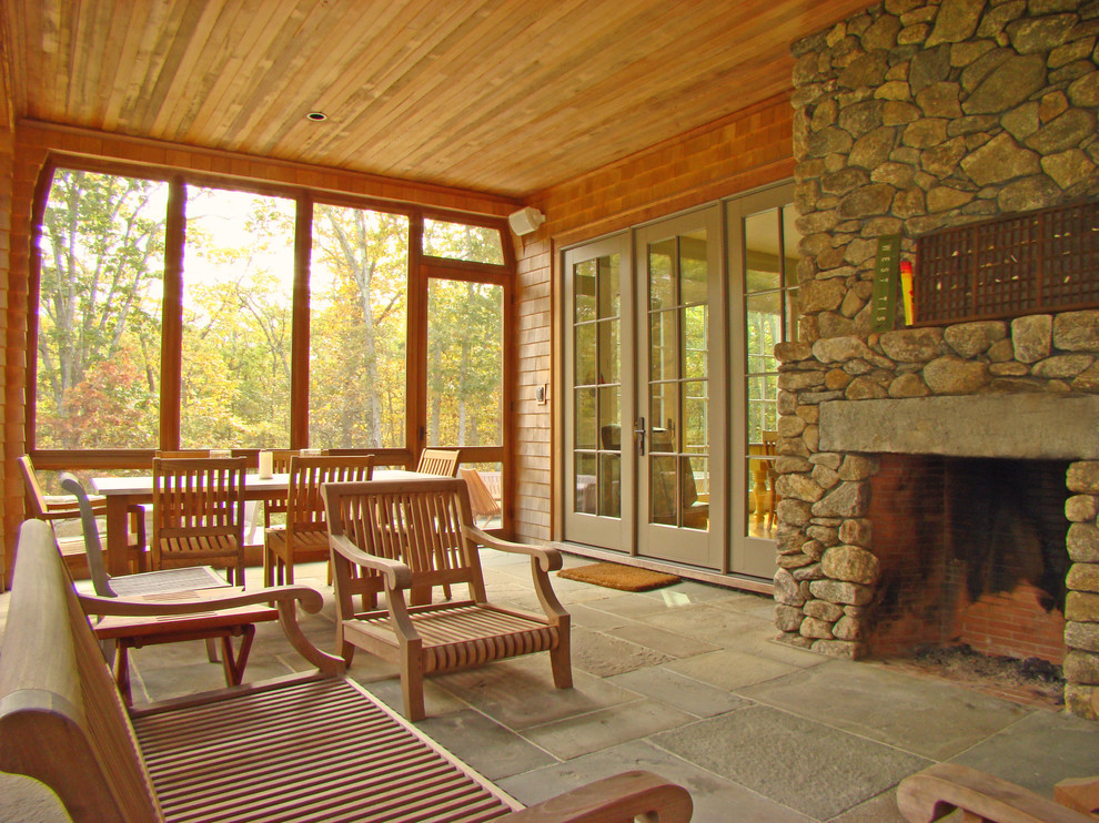 Cette photo montre un porche d'entrée de maison arrière chic de taille moyenne avec une cheminée, des pavés en béton et une extension de toiture.