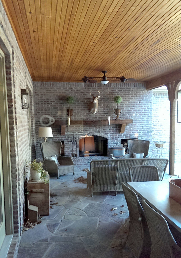 Aménagement d'un grand porche d'entrée de maison arrière campagne avec un foyer extérieur, des pavés en pierre naturelle et une extension de toiture.
