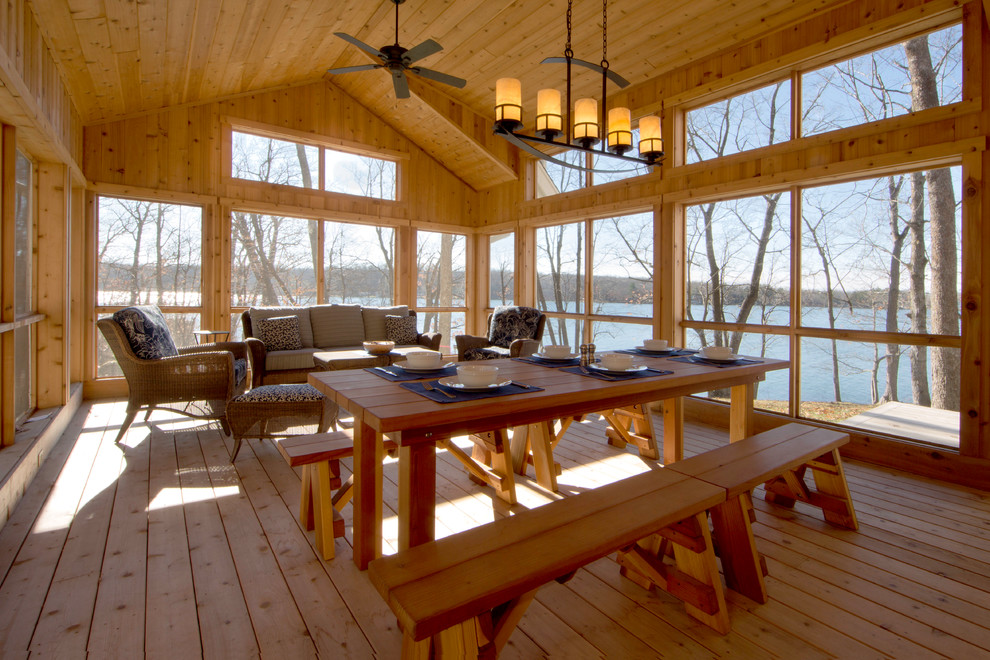 This is an example of a mid-sized rustic screened-in side porch design in Minneapolis with decking and a roof extension.