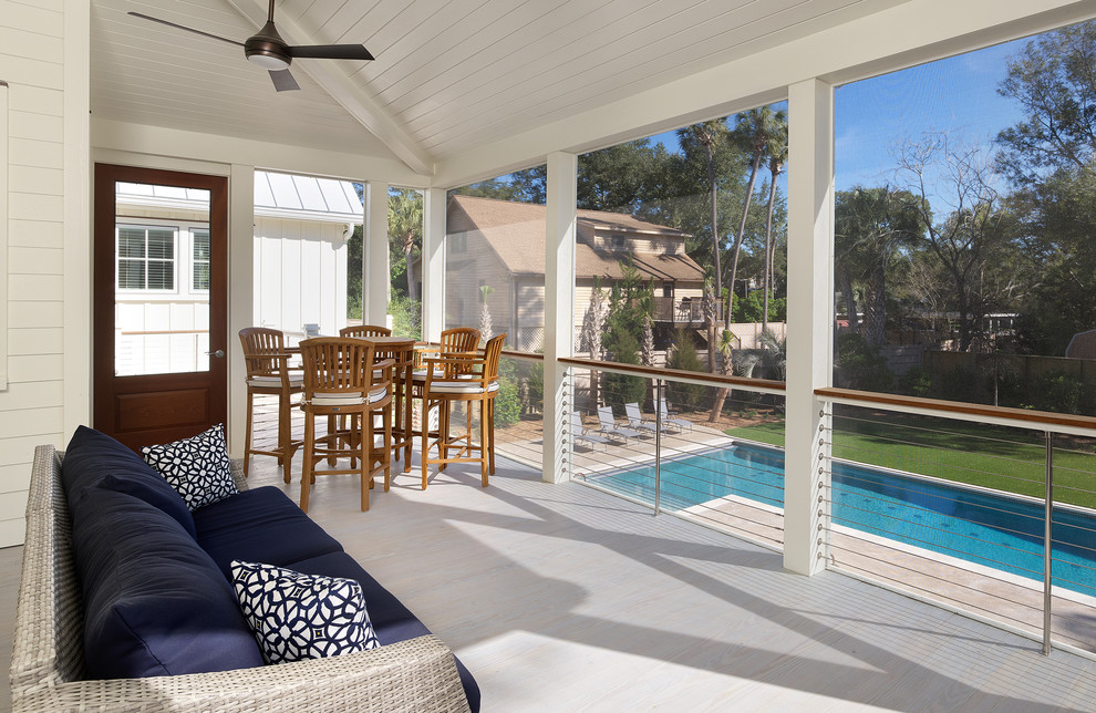 This is an example of a mid-sized coastal screened-in back porch design in Charleston with a roof extension.