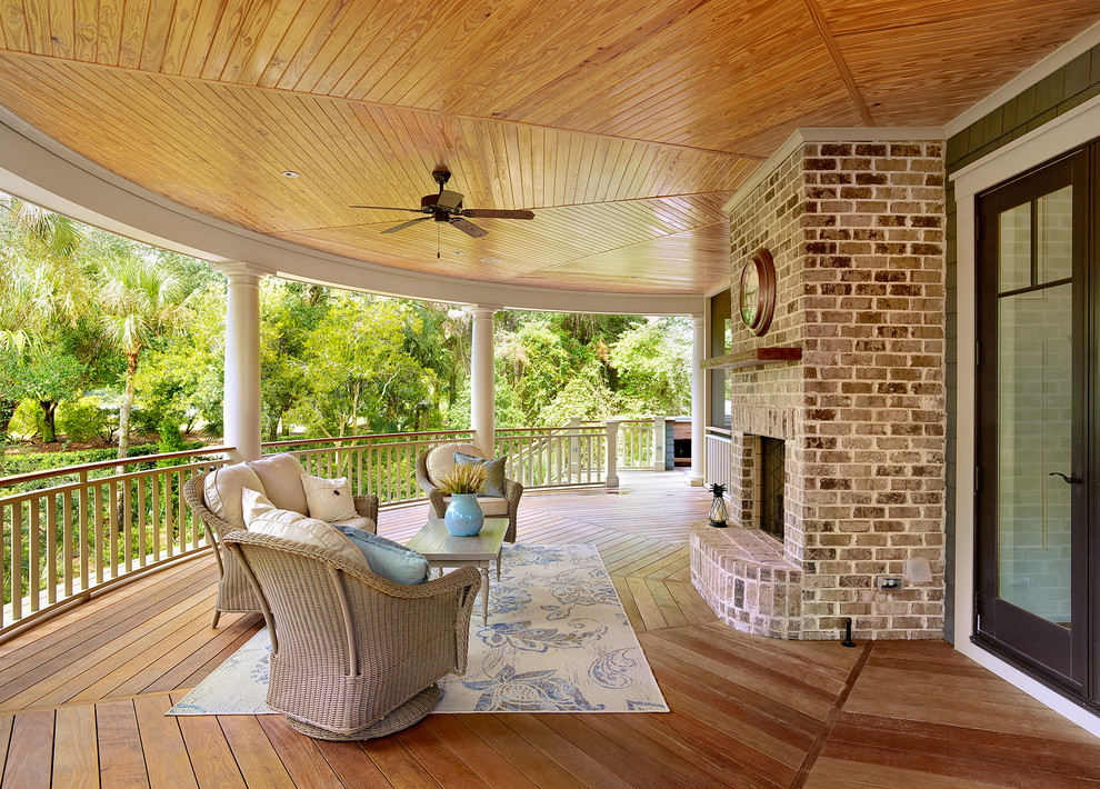 Exemple d'un grand porche d'entrée de maison victorien avec un foyer extérieur, une terrasse en bois et une extension de toiture.
