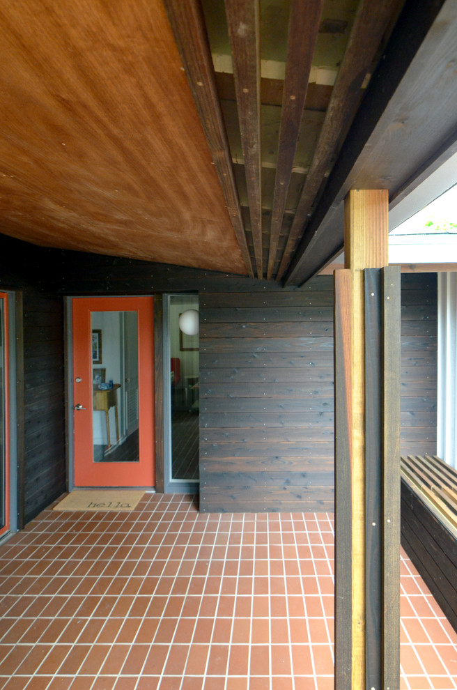 Immagine di un piccolo portico moderno davanti casa con un tetto a sbalzo e piastrelle