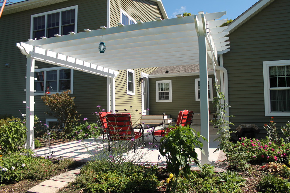 Photo of a classic back veranda in Milwaukee with concrete slabs and a pergola.