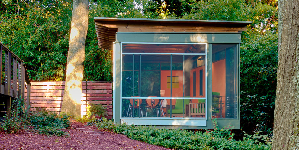 Ejemplo de porche cerrado moderno de tamaño medio en patio trasero y anexo de casas con entablado