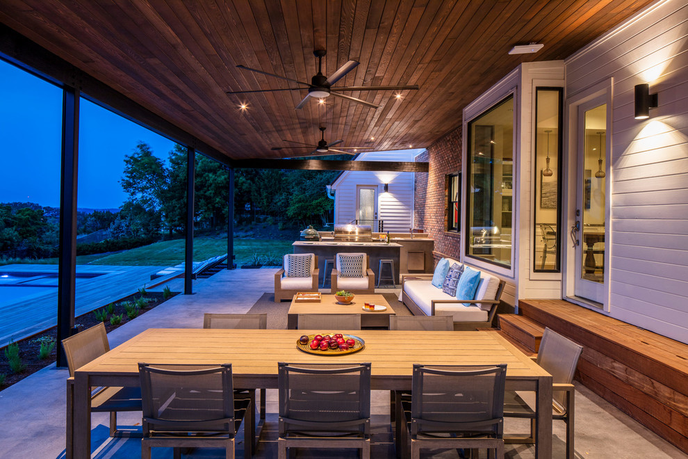 Inspiration pour un grand porche d'entrée de maison arrière design avec une cuisine d'été, une dalle de béton et un auvent.