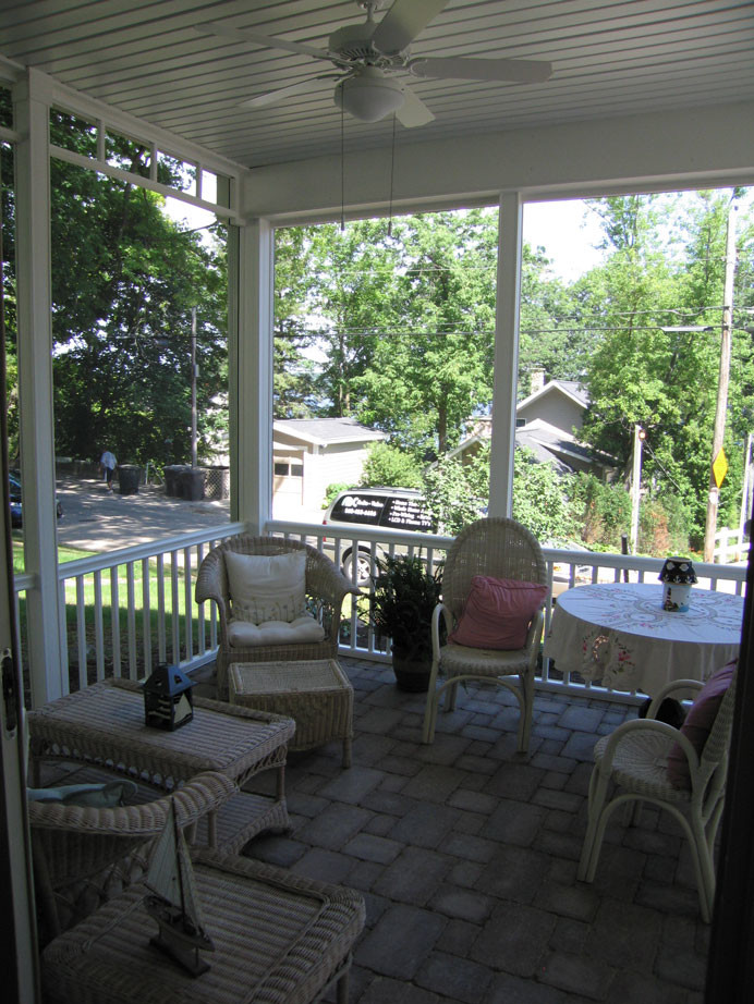 Mid-sized classic concrete paver screened-in side porch idea in Milwaukee with a roof extension