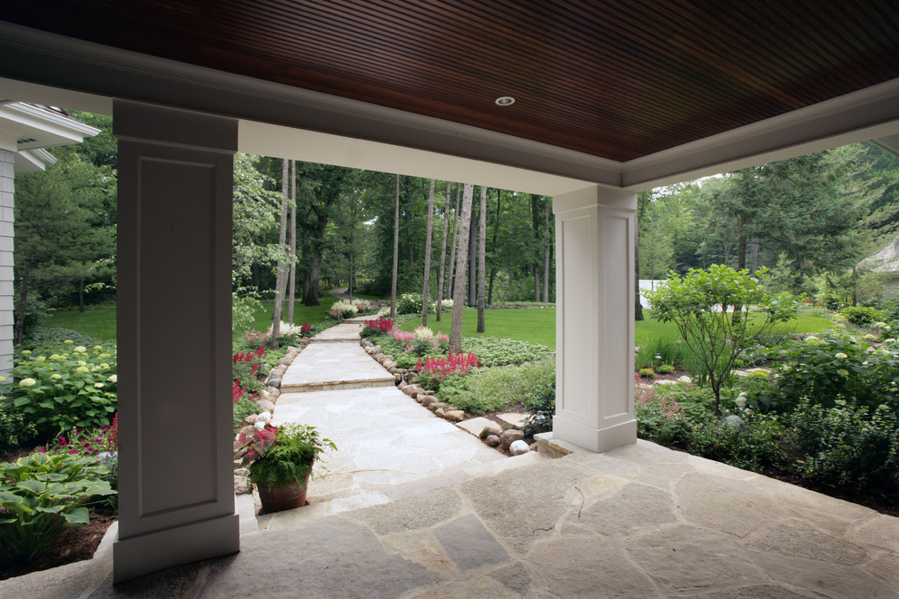 This is an example of a mid-sized traditional stone porch design in Milwaukee with a roof extension.