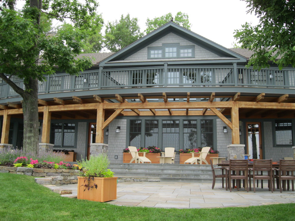 Cette image montre un grand porche d'entrée de maison arrière craftsman avec des pavés en béton et une pergola.