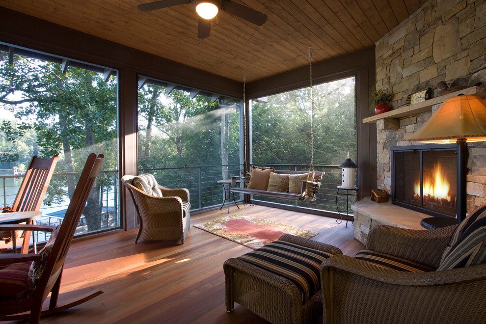 Réalisation d'un porche d'entrée de maison arrière tradition de taille moyenne avec une terrasse en bois, un foyer extérieur et une extension de toiture.