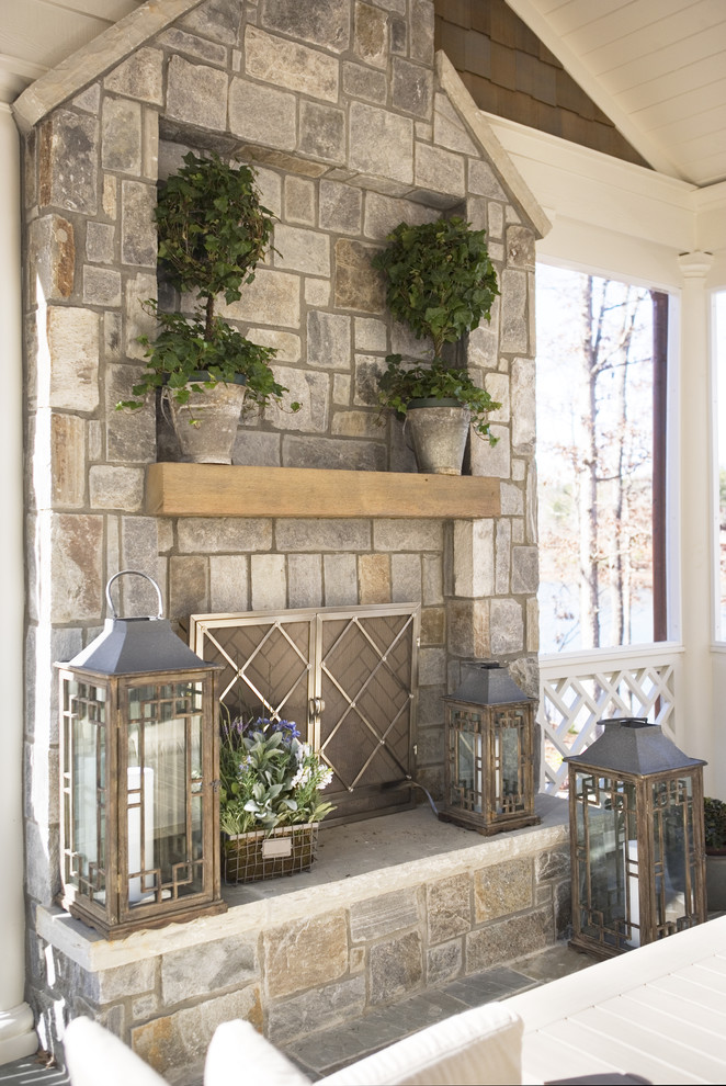 Idée de décoration pour un grand porche d'entrée de maison arrière avec des pavés en pierre naturelle, une extension de toiture et un foyer extérieur.