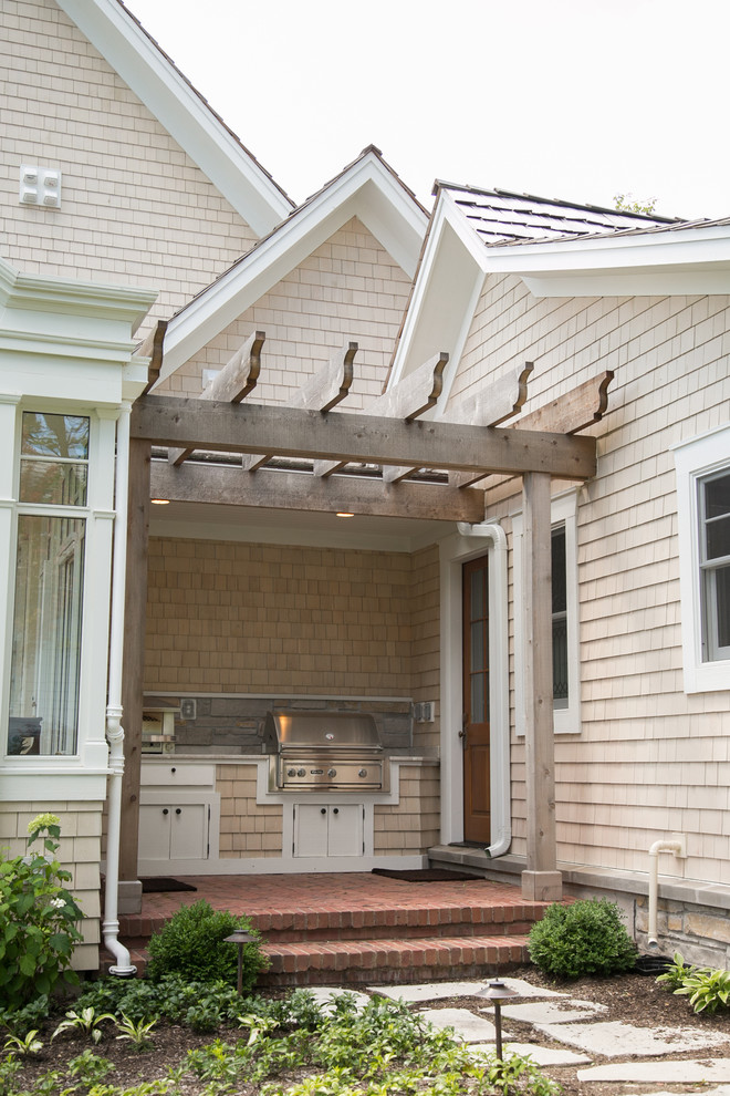 Exemple d'un petit porche d'entrée de maison latéral bord de mer avec une cuisine d'été, des pavés en brique et une pergola.