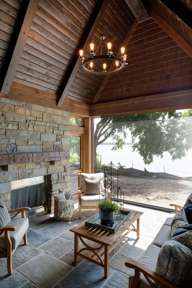 This is an example of a large rustic screened-in back porch design in Minneapolis with a roof extension.