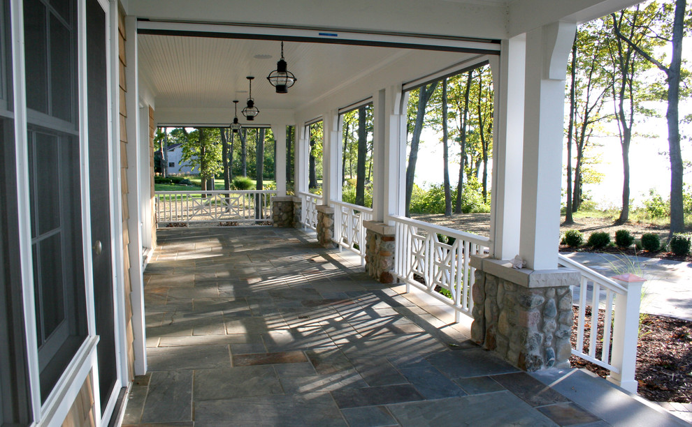 Immagine di un grande portico tradizionale davanti casa con pavimentazioni in pietra naturale e un tetto a sbalzo