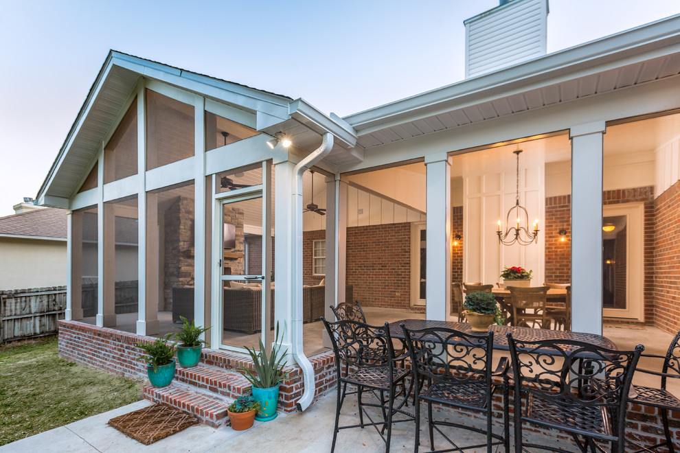 Large classic back screened veranda in Other with concrete slabs and a roof extension.
