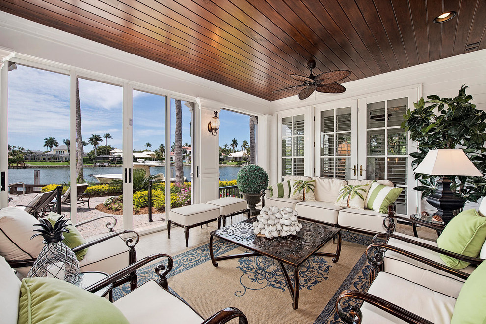 Large island style tile screened-in back porch idea in Miami with a roof extension
