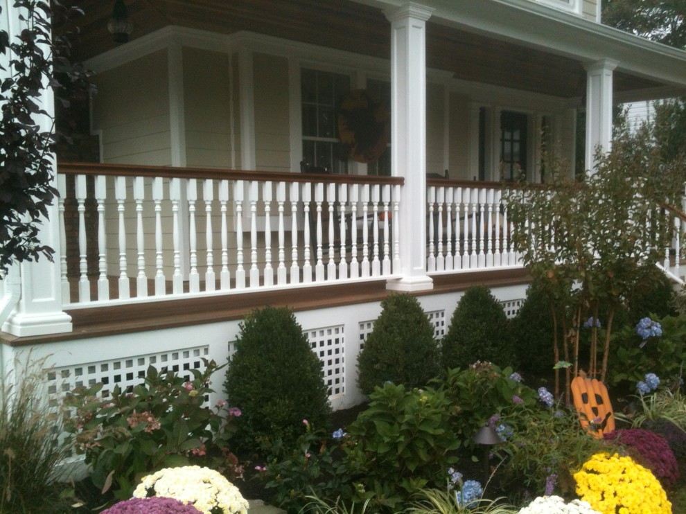 Exemple d'un grand porche d'entrée de maison avant chic avec une terrasse en bois et une extension de toiture.