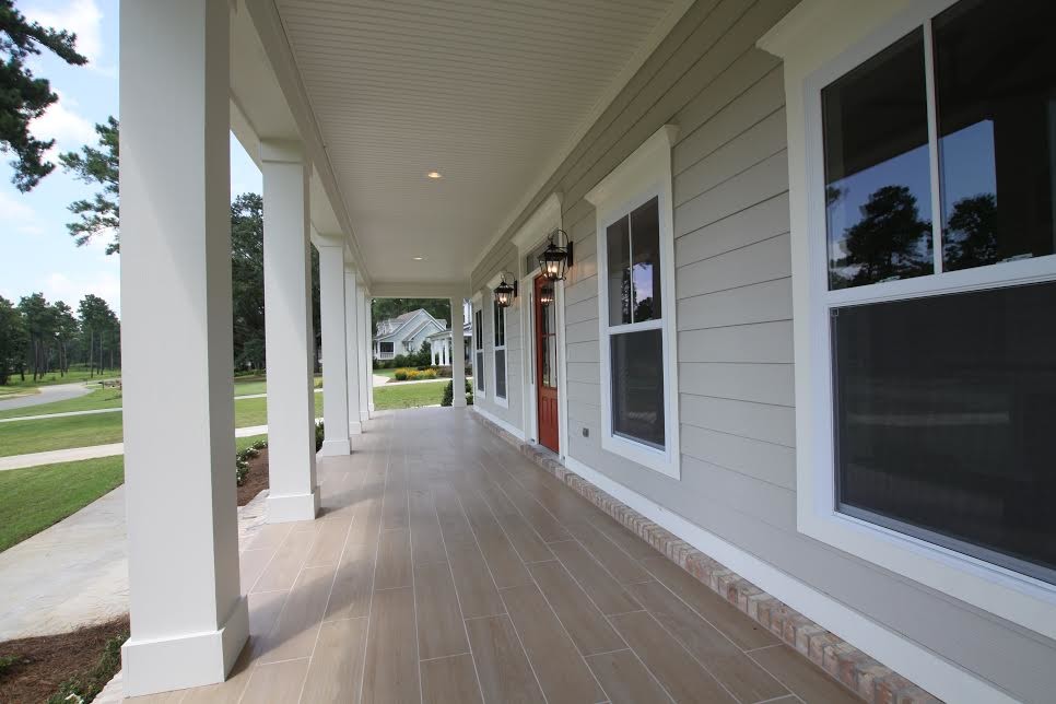 Cette image montre un grand porche d'entrée de maison avant traditionnel avec une terrasse en bois et une extension de toiture.