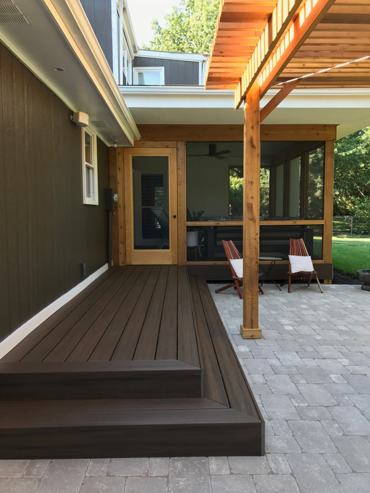 This is an example of a mid-sized contemporary concrete paver screened-in back porch design in Kansas City with a roof extension.