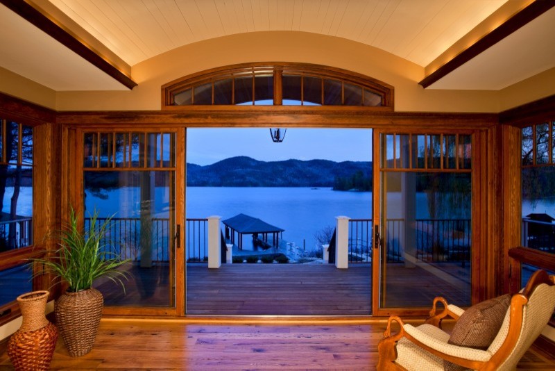 Réalisation d'un grand porche d'entrée de maison arrière tradition avec une terrasse en bois.