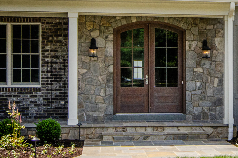 Foto di un portico country davanti casa con pavimentazioni in pietra naturale e un parasole