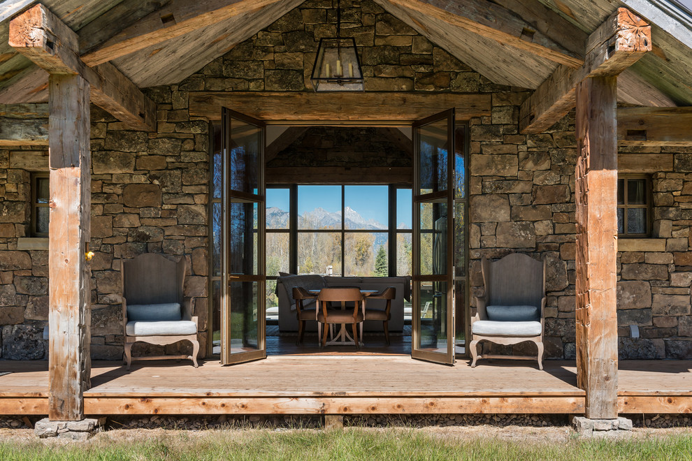 Inspiration pour un grand porche d'entrée de maison latéral chalet avec une terrasse en bois et une extension de toiture.