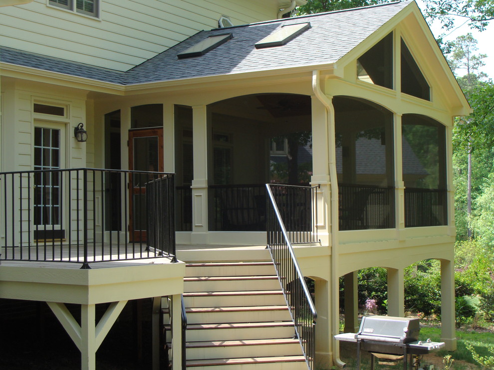 This is an example of a large transitional screened-in back porch design in Raleigh with a roof extension.