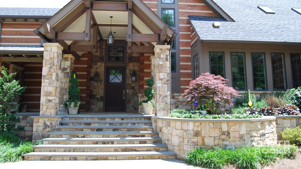 Immagine di un grande portico stile rurale davanti casa con pavimentazioni in pietra naturale e un tetto a sbalzo