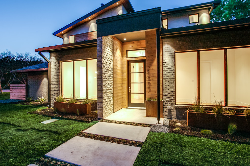 Inspiration for a large modern concrete paver front porch remodel in Dallas with a roof extension