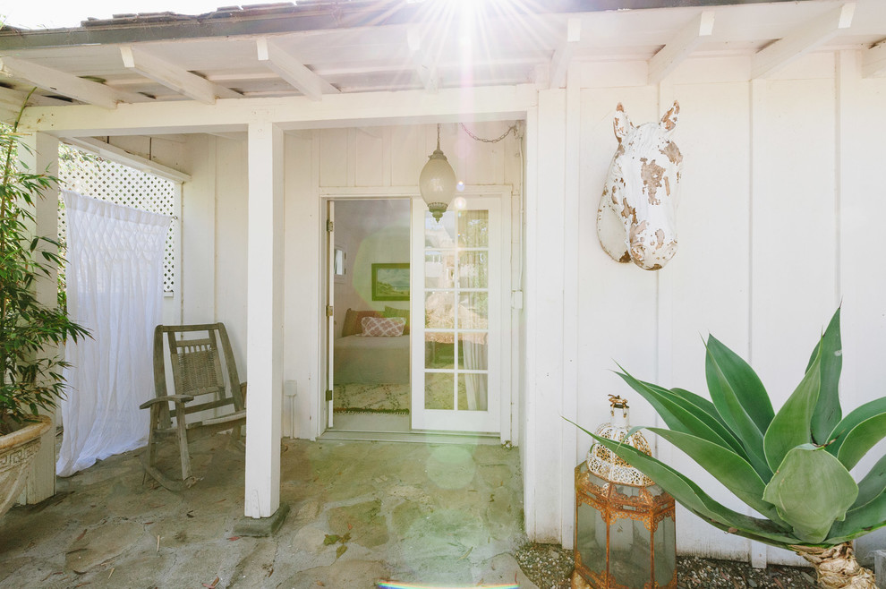 На фото: веранда на заднем дворе в стиле фьюжн с покрытием из каменной брусчатки и козырьком