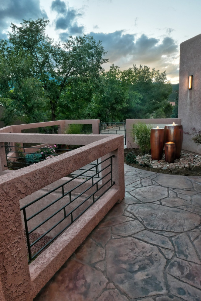 Ejemplo de terraza de estilo americano de tamaño medio en patio delantero con suelo de hormigón estampado y fuente