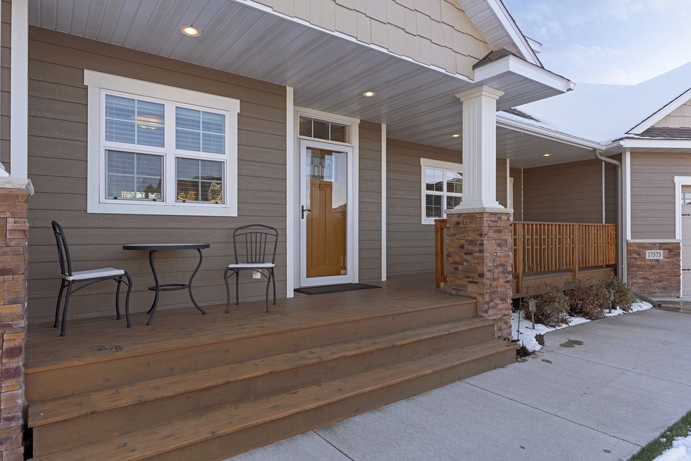 Cette photo montre un grand porche d'entrée de maison avant craftsman avec une terrasse en bois et une extension de toiture.