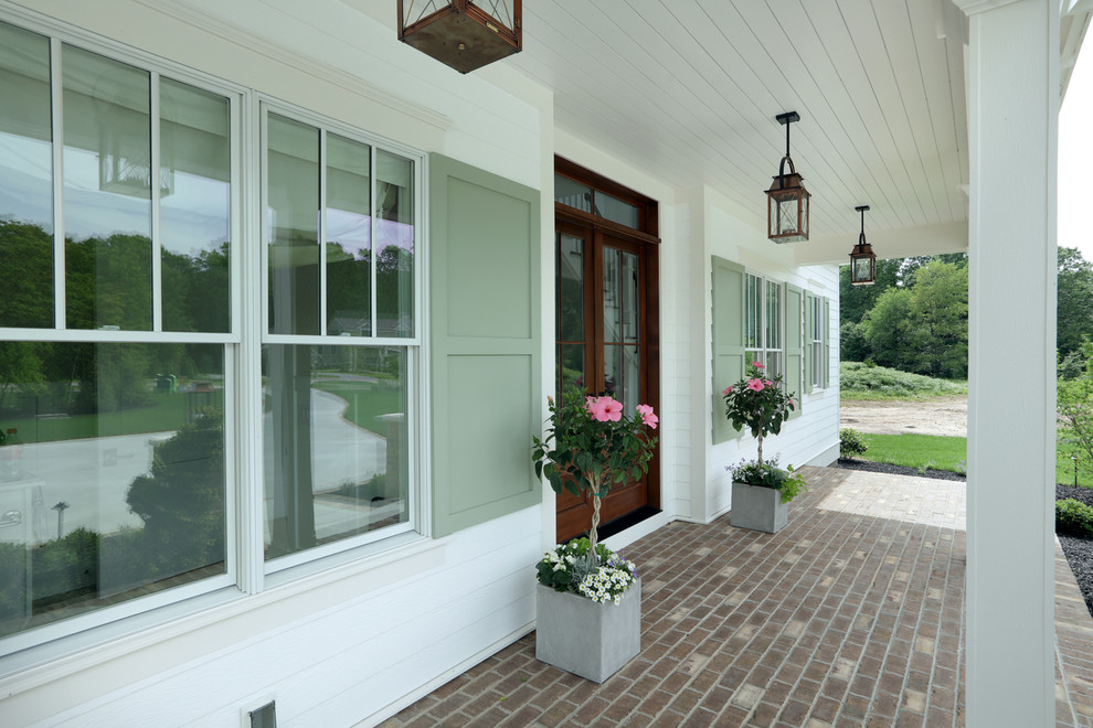 Inspiration pour un porche d'entrée de maison avant rustique de taille moyenne avec des pavés en brique et une extension de toiture.