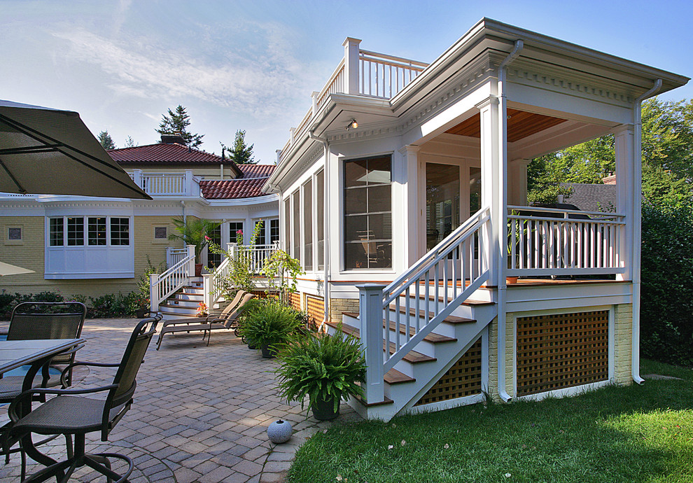 Immagine di un portico classico di medie dimensioni e dietro casa con un portico chiuso, pavimentazioni in mattoni e un tetto a sbalzo