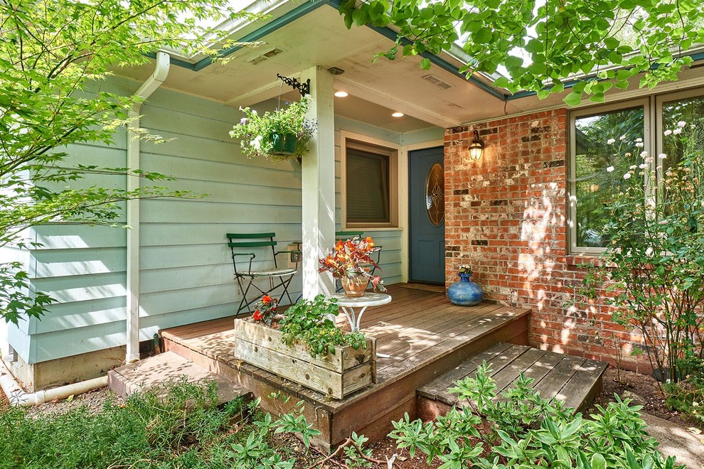Cette photo montre un petit porche avec des plantes en pot avant chic avec une terrasse en bois et une extension de toiture.