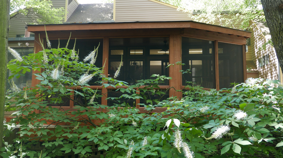 Aménagement d'un grand porche d'entrée de maison arrière craftsman avec une moustiquaire, une terrasse en bois et une extension de toiture.