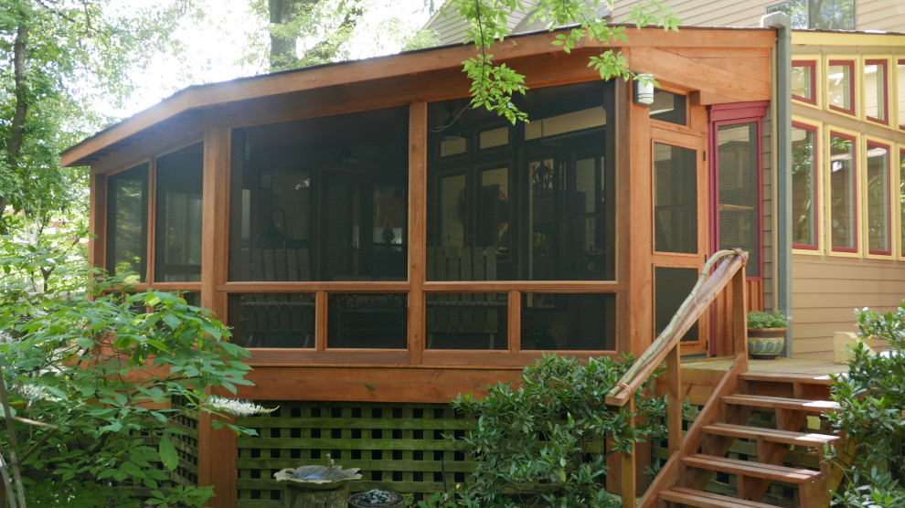 Immagine di un grande portico american style dietro casa con un portico chiuso, pedane e un tetto a sbalzo